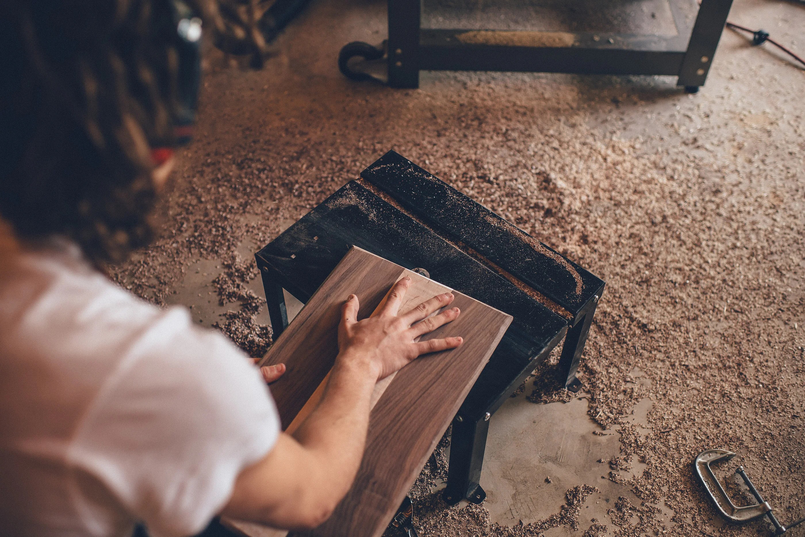 Handwerker glättet ein Holzstück an einer Werkbank mit sichtbaren Holzspänen